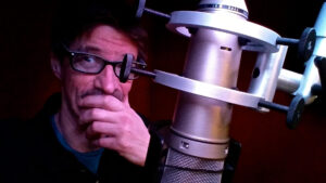 Marc in a dark studio behind a microphone.